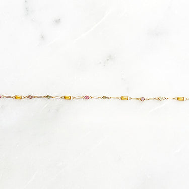 Gold bracelet with colorful sapphire on a white marble surface