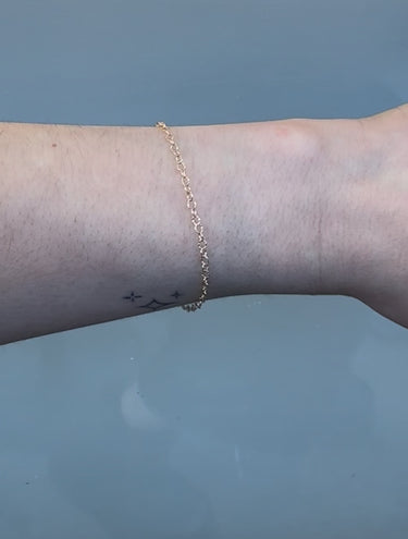Gold chain on a person's wrist on a white background