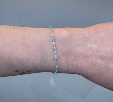 Silver chain with blue beads on a person's wrist