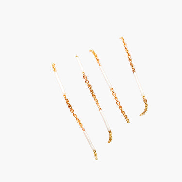 Gold chain necklace with white beads on a light gray background
