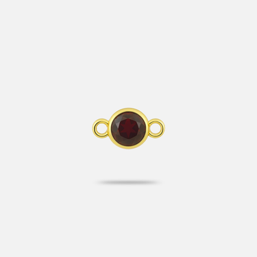 A small yellow gold connector charm with a round, faceted 3.4mm garnet.