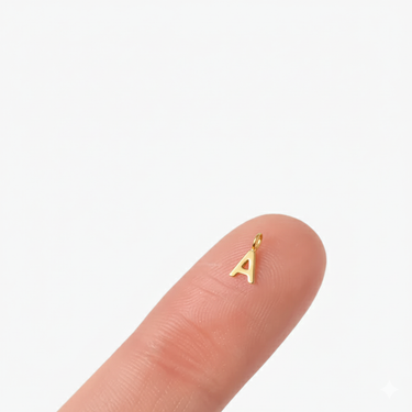 Mini 14K alphabet dangle charm initial A, fingertip for scale.