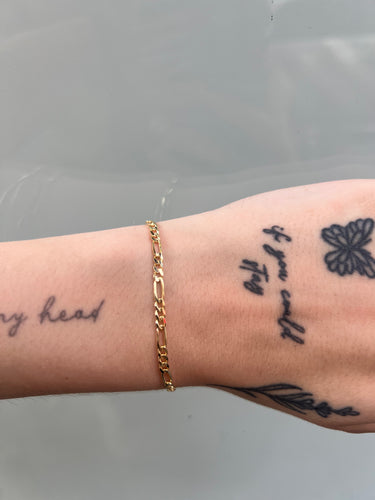 14k gold figaro style chain on wrist