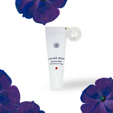 Lip care balm with a pearl on a white background surrounded by purple flowers