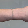 Silver chain with gold beads on a person's wrist on grey background
