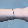 Black chain with silver beads on a person's wrist on grey background