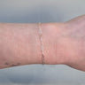 Silver paperclip chain on a person's wrist on a white background