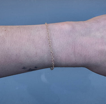 Gold chain on a person's wrist on a white backgriound