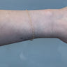 Gold chain on a person's wrist on a white background