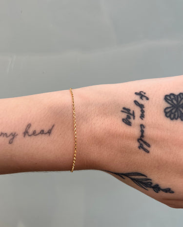 gold cable chain with oval shaped links on wrist