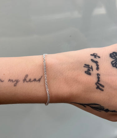 thin silver curb chain on wrist