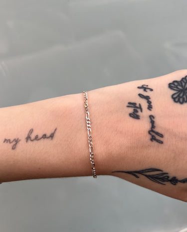 Silver figaro style chain on wrist