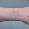 Silver chain with blue beads on a person's wrist 