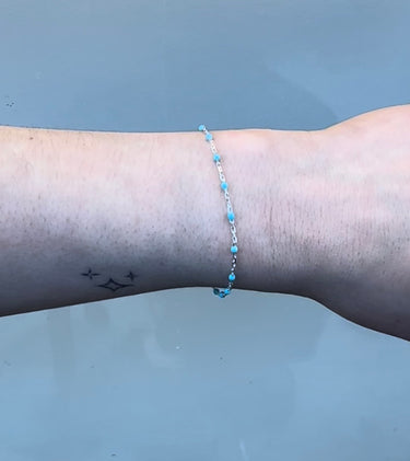 Silver chain with blue beads on a person's wrist 