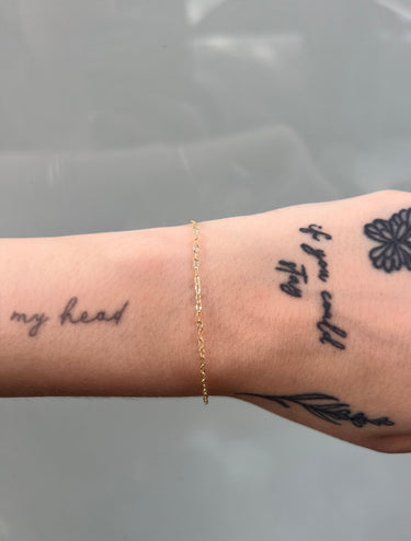 Gold dainty starburst link chain on a wrist