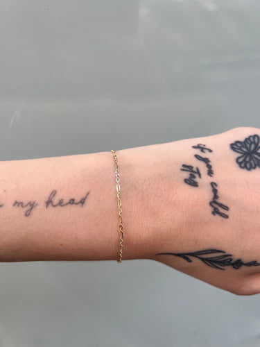 14k white and yellow gold figaro chain on a wrist