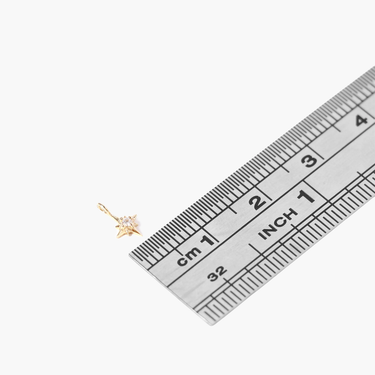 A 14k yellow gold north star charm with a natural diamond with ruler for sclae (less than 5mm wide).