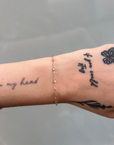 Gold chain necklace with opal resin on a wrist