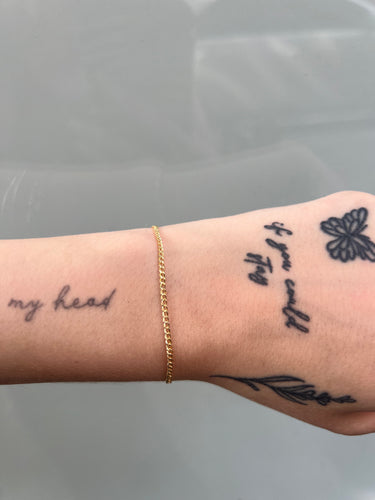 Gold diamond cut curb chain on a wrist