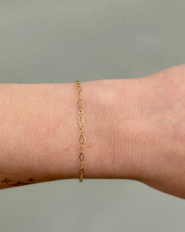 gold chain with diamond shaped links on a wrist