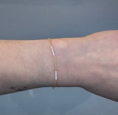 Gold cable chain with white enamel on a wrist