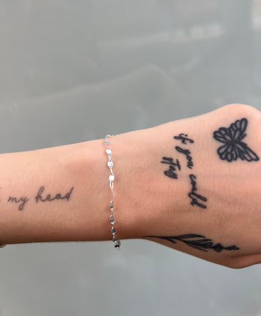 silver chain with flat shiny links on a wrist