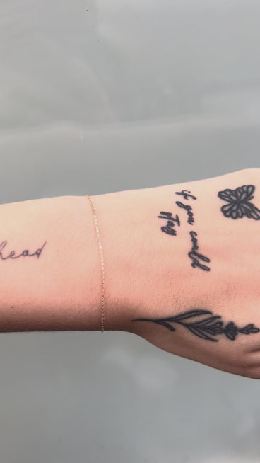 Dainty gold cable chain on a wrist